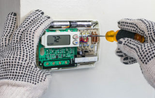 hands repairing a thermostat