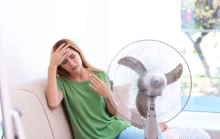 a woman sweating by a fan
