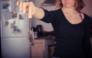 a woman holding a dead rat
