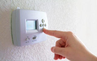 a finger adjusting a thermostat