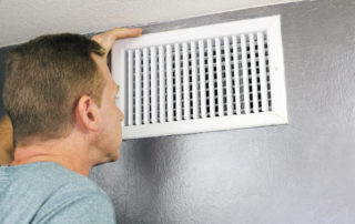 a man looking at an air vent