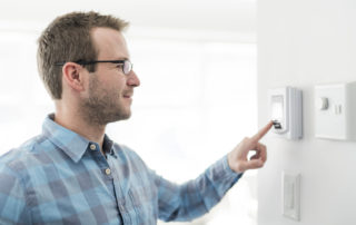 a man adjusting a thermostat
