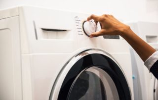a hand adjusting a washing machine knob