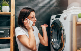 a woman on the phone confused near a washer