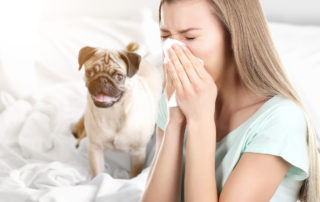 a woman sneezing next to a dog