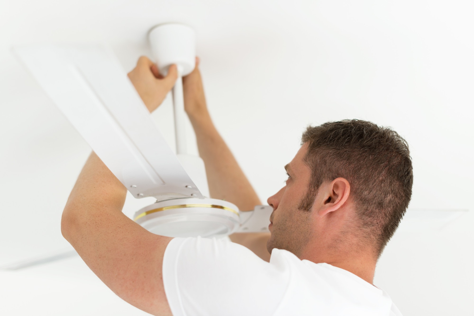 a man inspecting a ceiling fan