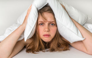 a woman holding a pillow over her ears
