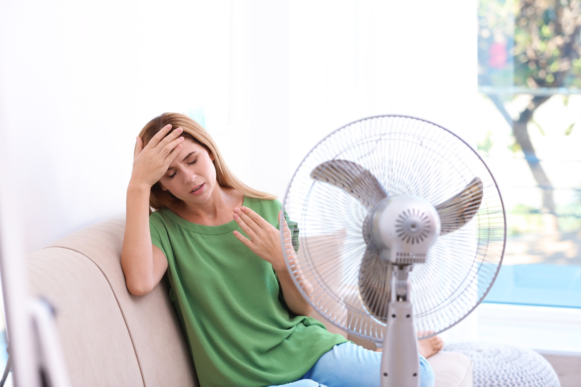 a woman sweating by a fan